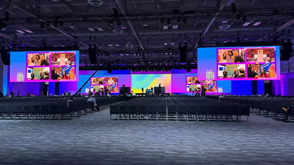 Conference stage design with large video screens, lighting, camera positions, rigging, and audience seating