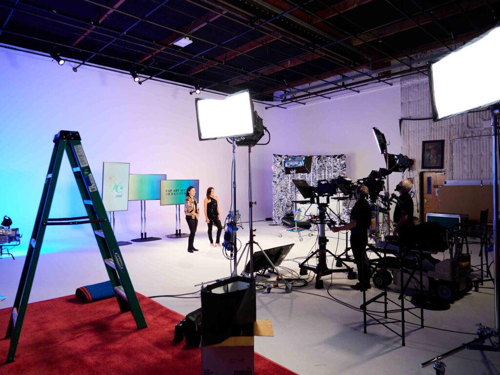 Corporate video production in a studio with broadcast cameras, LED lighting, and presenters on set.